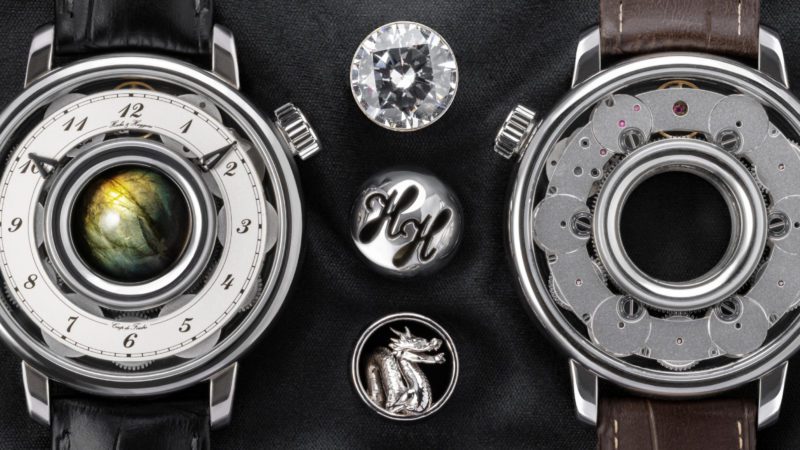 Hooke & Huygens est une nouvelle marque de montres mécaniques de luxe suisses avec des joyaux personnels qui sont facilement échangés dans le centre de la montre annulaire avec huit barillets. Les gemmes sont personnalisées pour chaque montre, soit de billes de pierres naturelles de 15 mm soit de billes de métal, soit sculptures ou pierres précieuses dans un cadre.
Le mouvement annulaire semi-squelette breveté dispose de 8 barillets à remontage manuel élégamment connectés, offrant une réserve de marche de près d'une semaine.
Les prix commencent à CHF 26'400 pour le boîtier en acier CHF 42'800 pour or.